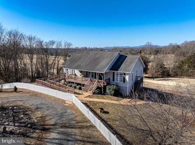 view of front of property with a shingled roof, fence private yard, and stairway