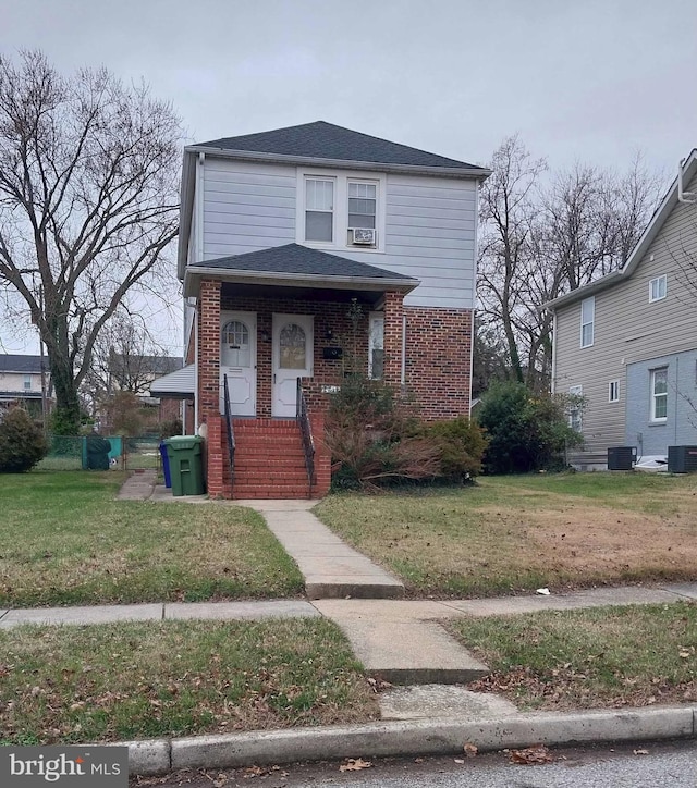 view of front of property with brick siding, a front yard, and central air condition unit