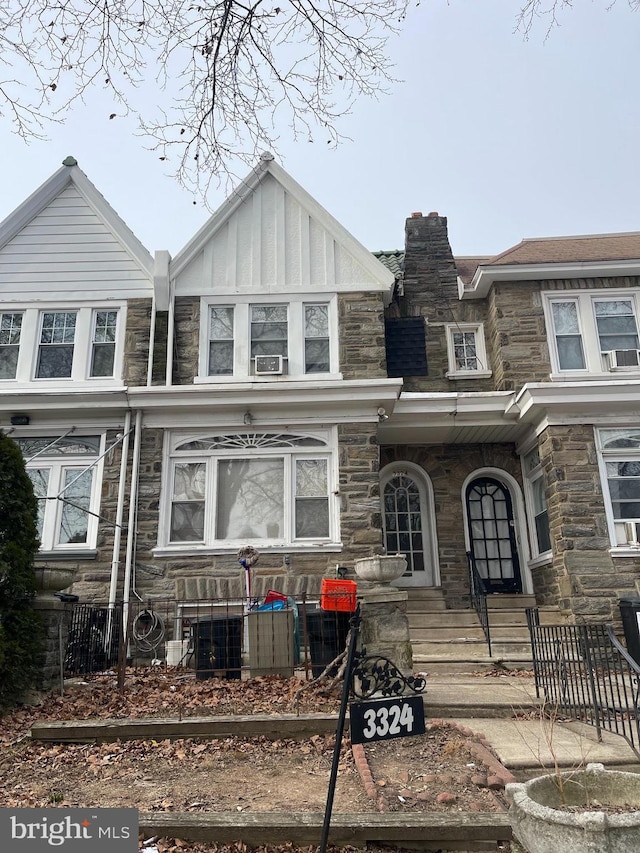 multi unit property featuring stone siding, a chimney, and board and batten siding