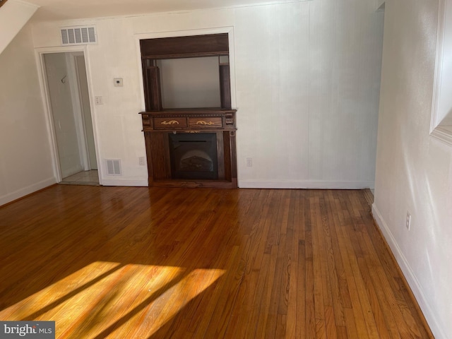 unfurnished living room with a fireplace, visible vents, and wood finished floors