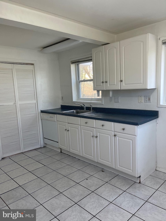 kitchen featuring dark countertops, white cabinets, white dishwasher, and a sink