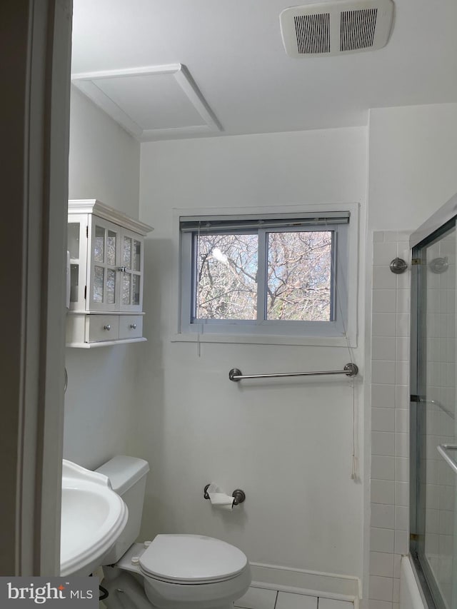 bathroom featuring shower / bath combination with glass door, visible vents, a sink, and toilet