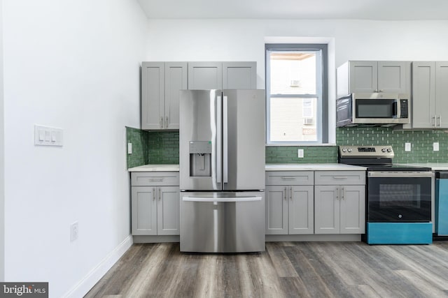 kitchen with stainless steel appliances, wood finished floors, light countertops, and gray cabinetry