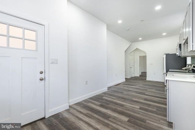 kitchen featuring arched walkways, recessed lighting, dark wood-style flooring, white cabinets, and light countertops