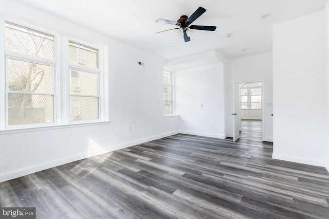 empty room featuring dark wood-style flooring, a ceiling fan, and baseboards