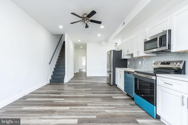 kitchen with tasteful backsplash, light countertops, appliances with stainless steel finishes, white cabinets, and baseboards