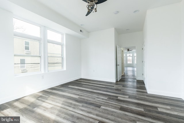 spare room with dark wood-style floors, visible vents, baseboards, and a ceiling fan