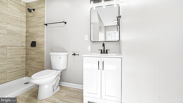 bathroom with toilet, a shower stall, baseboards, and vanity