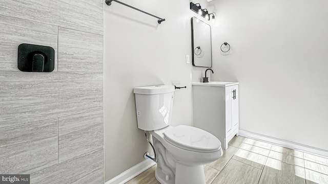 bathroom with vanity, toilet, and baseboards