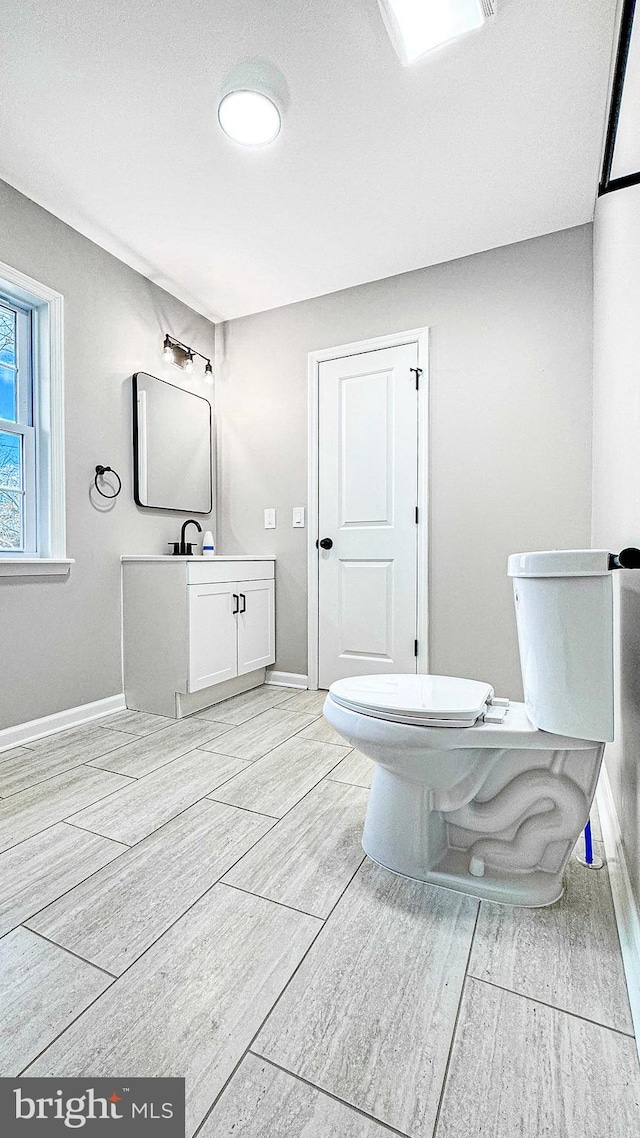 bathroom featuring vanity, toilet, and baseboards