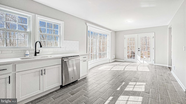 kitchen featuring dishwasher, light countertops, plenty of natural light, and a sink