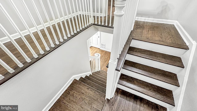 stairs with wood finished floors, visible vents, and baseboards