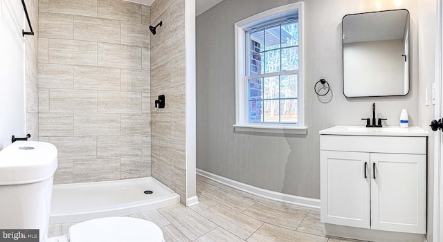 bathroom featuring baseboards, toilet, a shower stall, and vanity