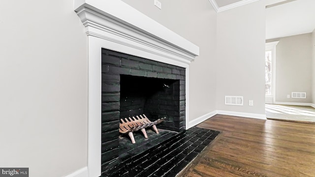 interior details featuring crown molding, wood finished floors, visible vents, and baseboards