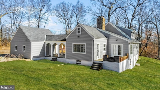 rear view of house featuring a shingled roof, a lawn, and a chimney