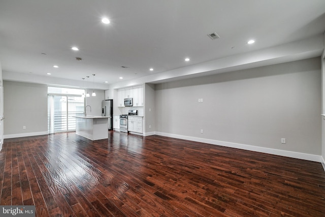 unfurnished living room with dark wood-style floors, baseboards, a sink, and recessed lighting