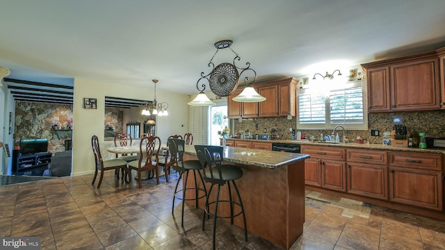 kitchen featuring decorative backsplash, a breakfast bar area, a center island, hanging light fixtures, and a sink