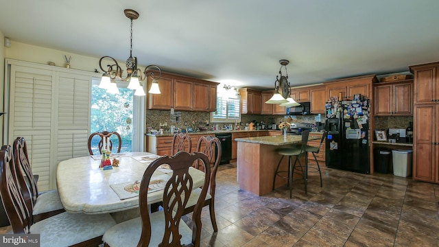 kitchen featuring tasteful backsplash, a kitchen island, brown cabinets, black appliances, and pendant lighting