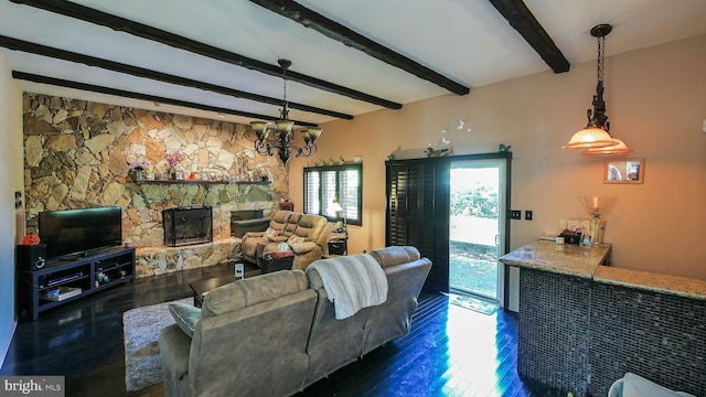 living room featuring dark wood finished floors, a stone fireplace, beamed ceiling, and an inviting chandelier