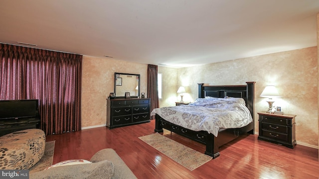 bedroom with visible vents, baseboards, and wood finished floors