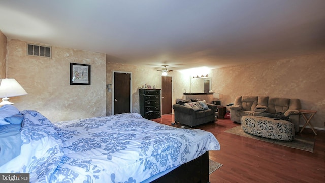 bedroom with a textured wall, dark wood finished floors, and visible vents