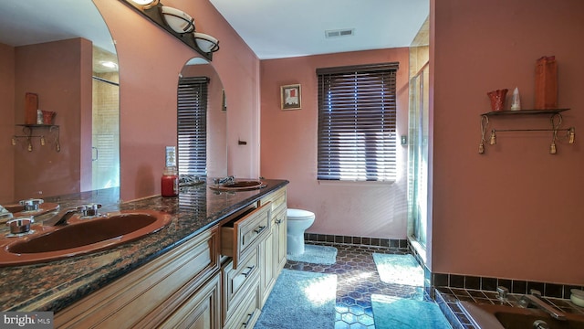 bathroom with visible vents, a sink, toilet, and double vanity