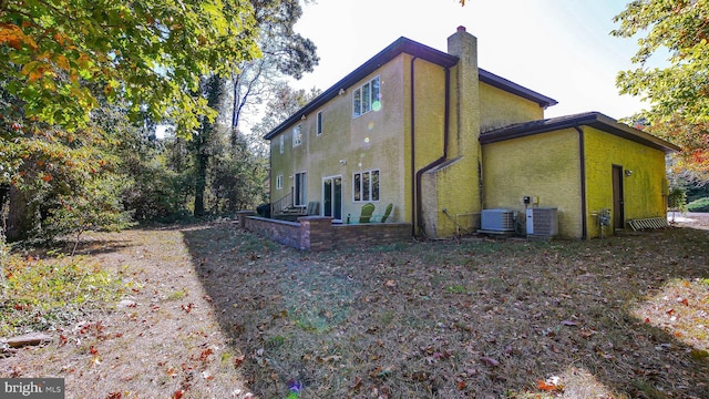 view of side of home featuring stucco siding, a chimney, and central air condition unit