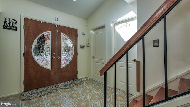 foyer entrance with lofted ceiling, french doors, and stairs