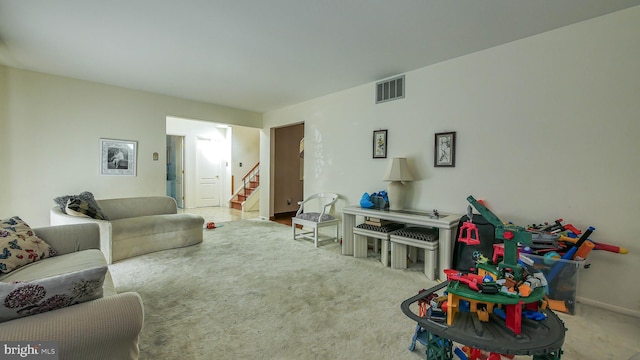 living room with visible vents, light carpet, and stairs