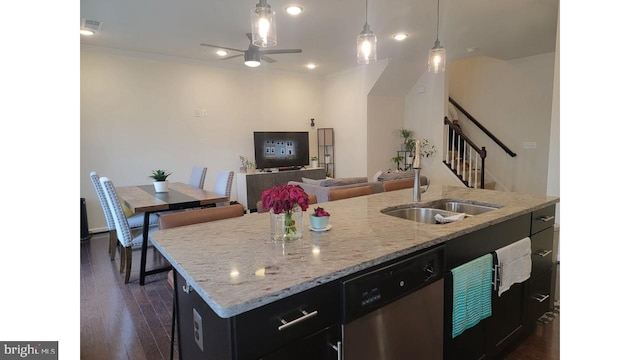 kitchen with pendant lighting, a center island with sink, stainless steel dishwasher, a sink, and dark cabinets