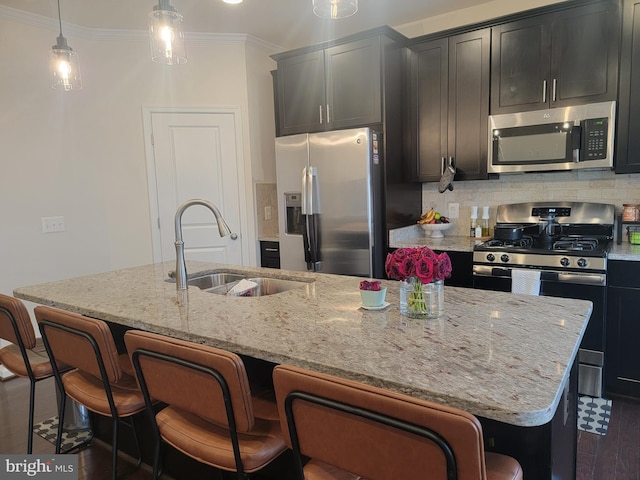 kitchen with appliances with stainless steel finishes, a sink, a kitchen island with sink, and decorative backsplash