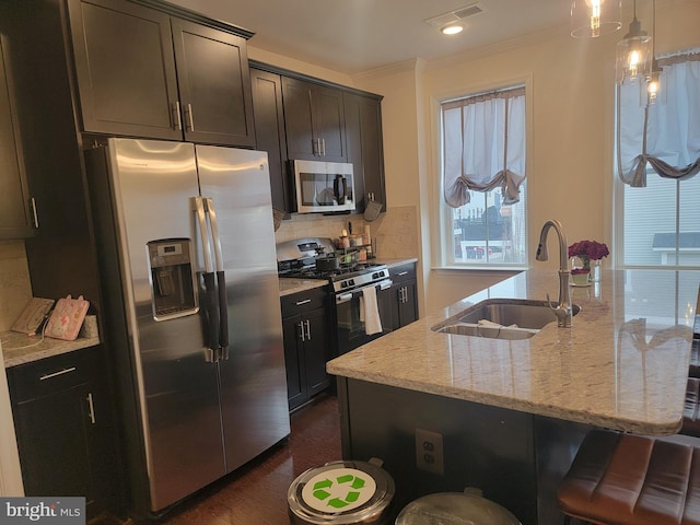 kitchen featuring a sink, visible vents, appliances with stainless steel finishes, tasteful backsplash, and a kitchen bar