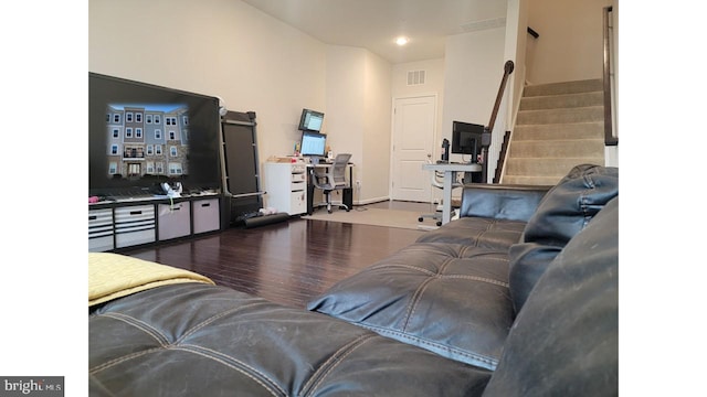 living room with stairs, visible vents, and wood finished floors