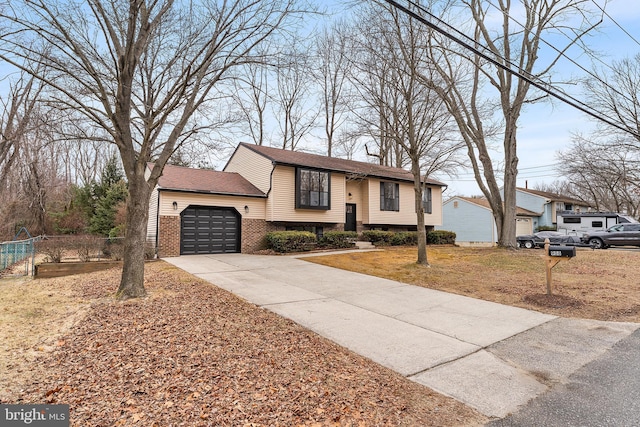 bi-level home with brick siding, an attached garage, and concrete driveway