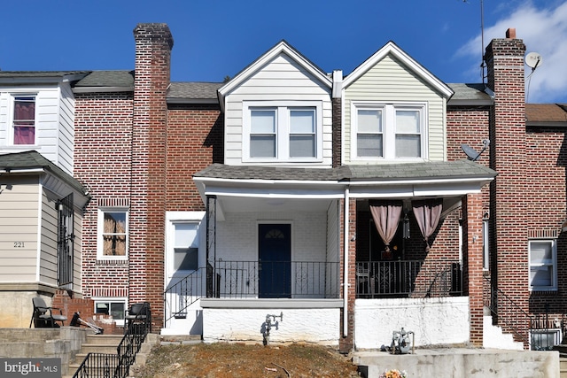 multi unit property featuring covered porch and brick siding