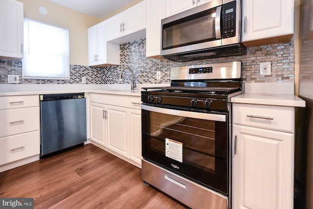 kitchen featuring white cabinets, appliances with stainless steel finishes, light countertops, and a sink