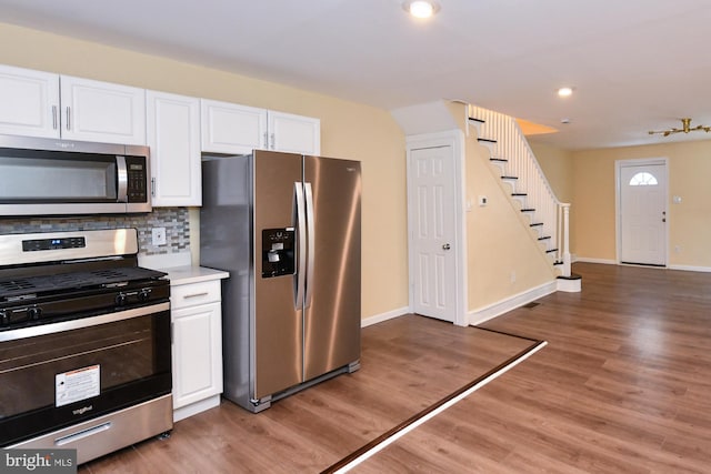 kitchen with appliances with stainless steel finishes, white cabinets, light countertops, and wood finished floors