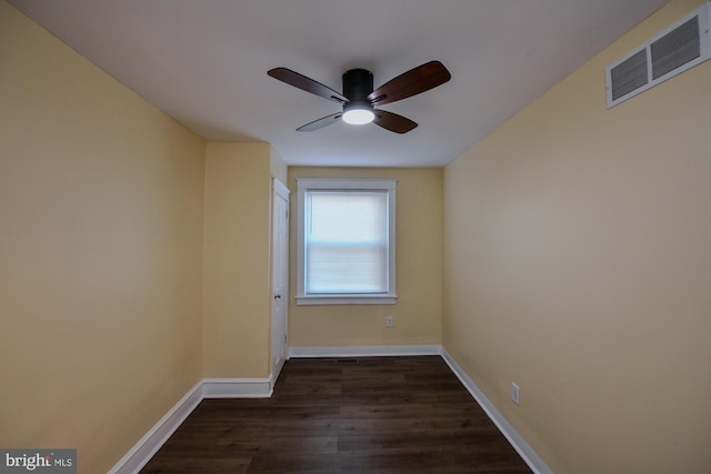 spare room with dark wood-style floors, a ceiling fan, visible vents, and baseboards