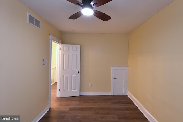 spare room with dark wood-style floors, visible vents, ceiling fan, and baseboards