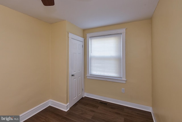 unfurnished room with a ceiling fan, dark wood-style flooring, visible vents, and baseboards