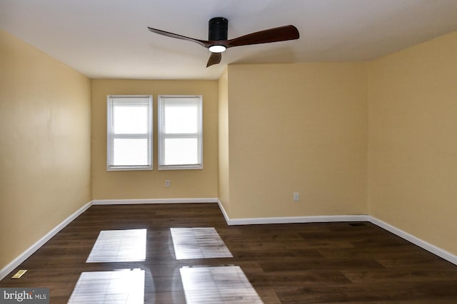 unfurnished room with dark wood finished floors, a ceiling fan, and baseboards