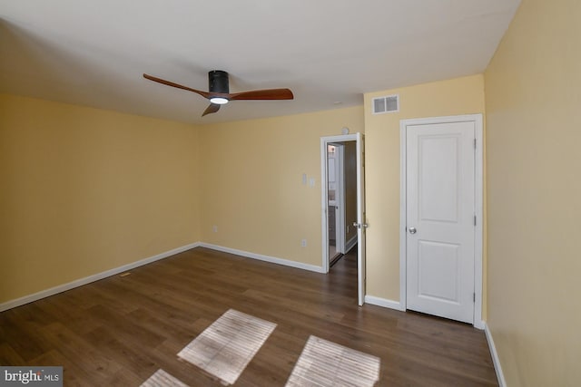 unfurnished bedroom with a ceiling fan, dark wood-style flooring, visible vents, and baseboards