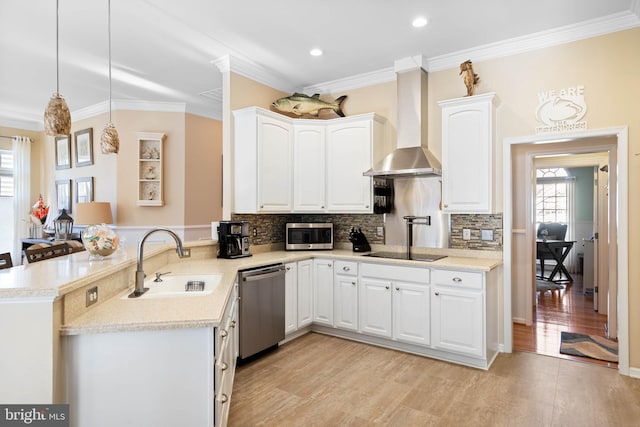 kitchen featuring a peninsula, a sink, appliances with stainless steel finishes, wall chimney range hood, and backsplash