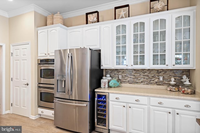 kitchen with beverage cooler, stainless steel appliances, white cabinetry, ornamental molding, and tasteful backsplash