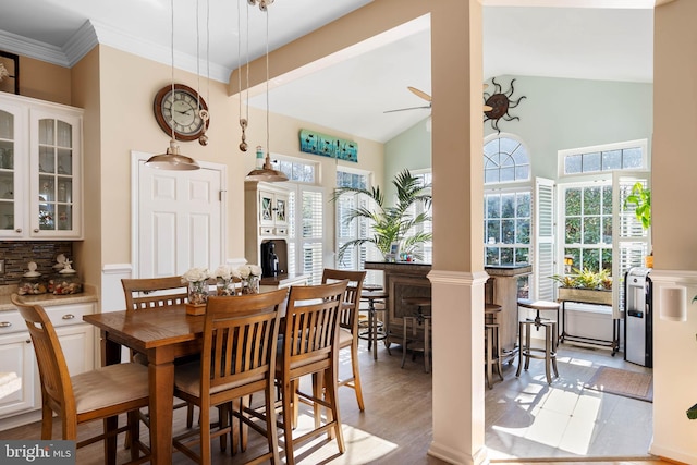 dining space with ornamental molding, light wood-style floors, vaulted ceiling, and ceiling fan