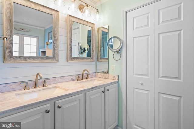 bathroom with double vanity, a closet, ornamental molding, and a sink