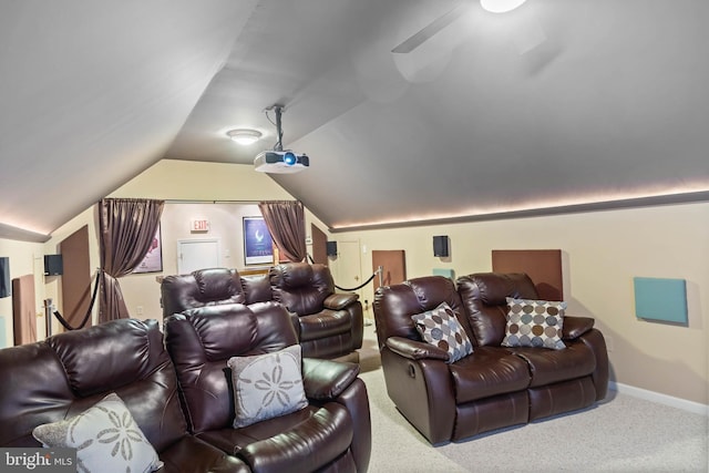 carpeted home theater room featuring lofted ceiling and baseboards