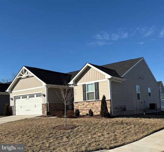 craftsman-style house featuring a garage, central AC unit, concrete driveway, stone siding, and board and batten siding