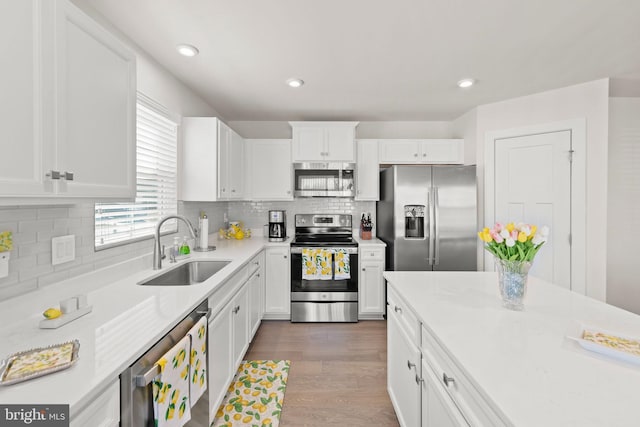 kitchen with stainless steel appliances, dark wood-style flooring, a sink, and white cabinets