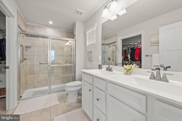 bathroom with double vanity, visible vents, a walk in closet, and a sink